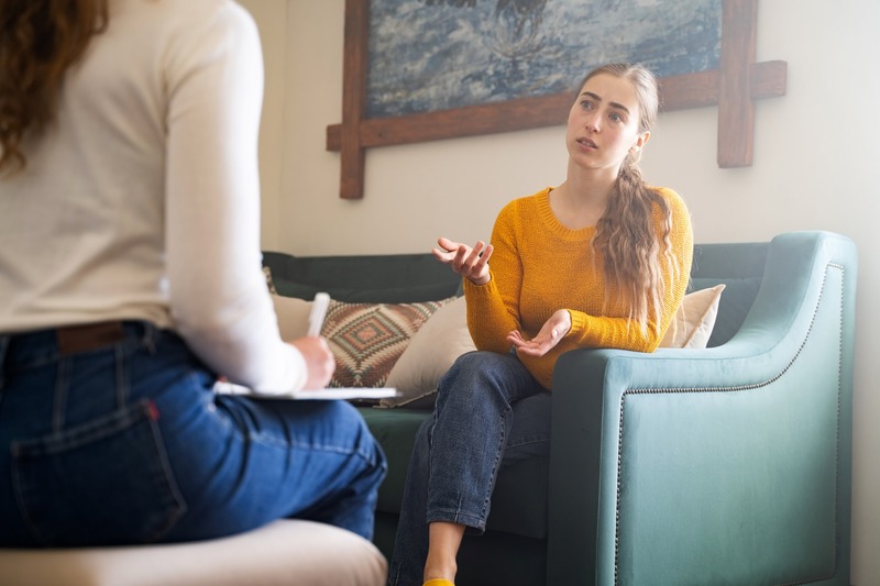 A young woman talking with a caring staff member in a comfortable counseling room